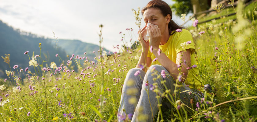Homeopathic Allergy Relief - Woman blowing her nose in a field