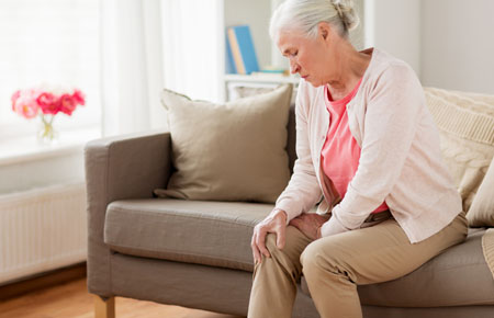 Homeopathic medicine for muscular pain - elderly woman holding her knee